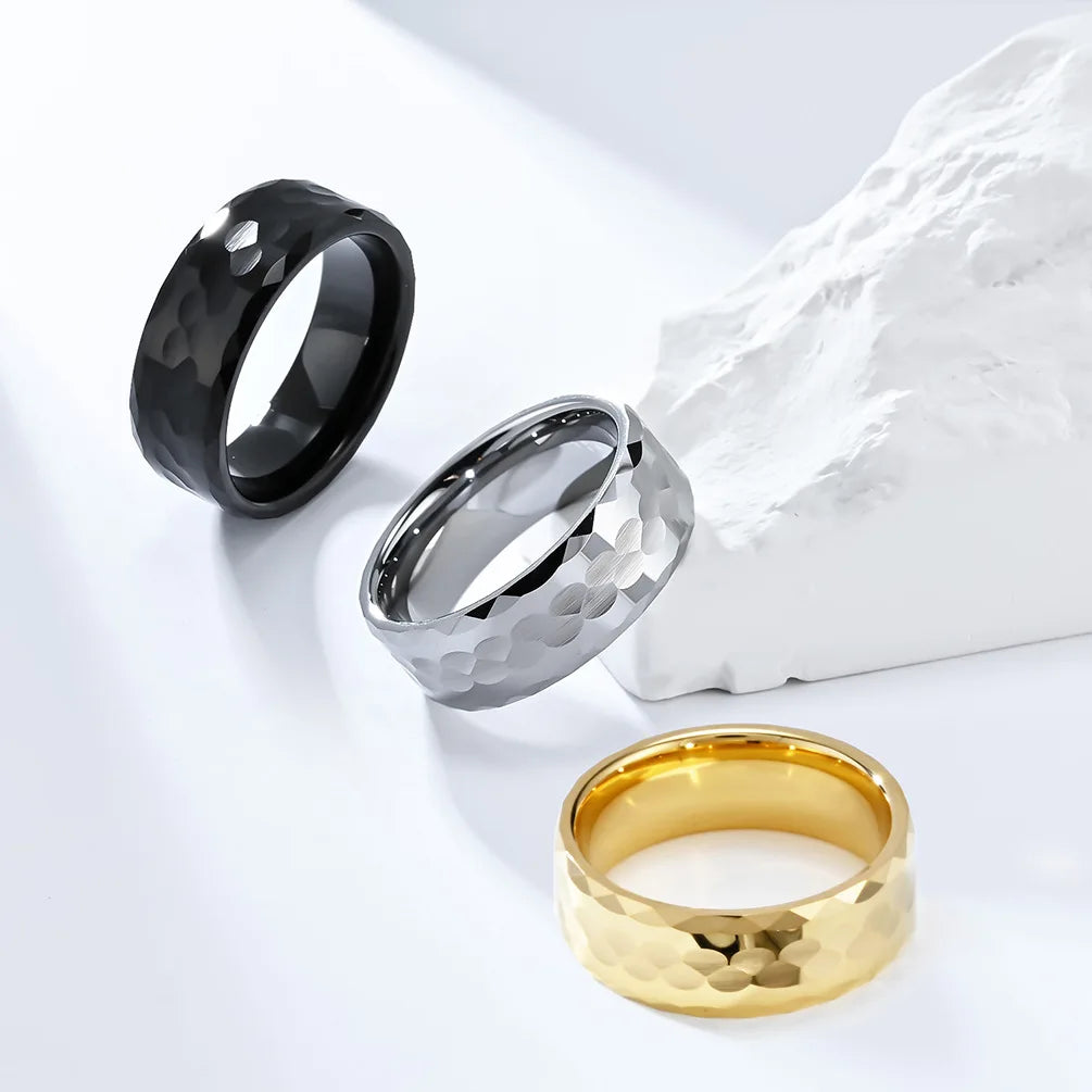 Trio of 8mm Tungsten men's rings in black, silver, and gold with hammered faceted designs.