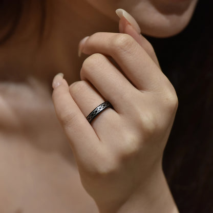 Black Tungsten unisex ring with intricate Celtic braid, 4mm width, displayed on a woman's hand.