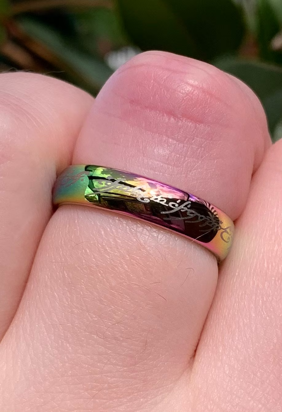 Close-up of a rainbow-colored Lord of the Rings replica ring on a finger