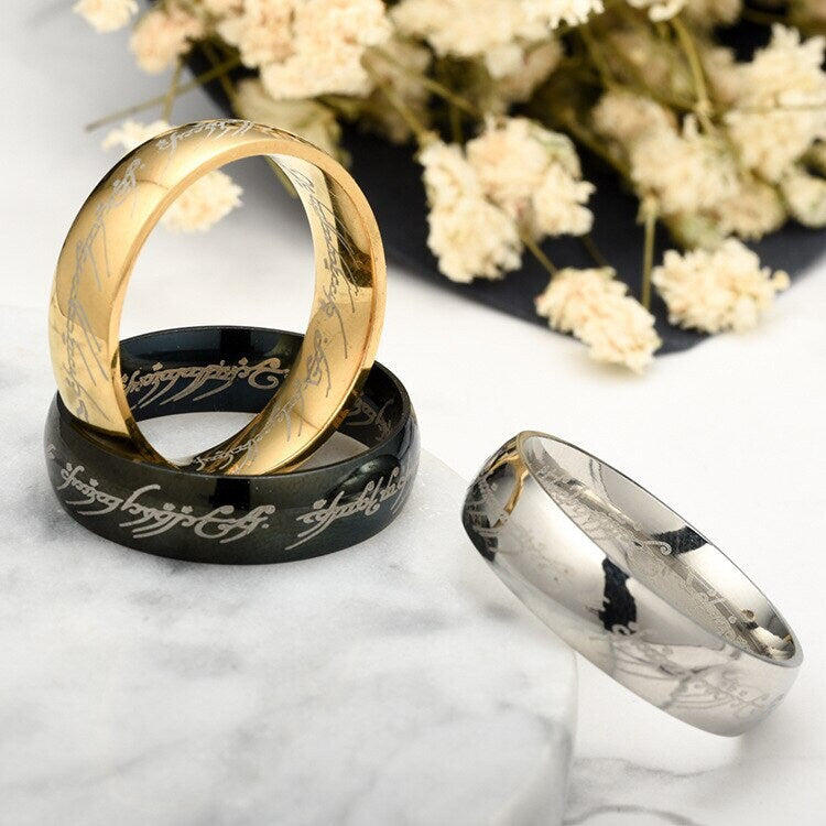 A set of Lord of the Rings One Ring replicas in black, gold, and silver