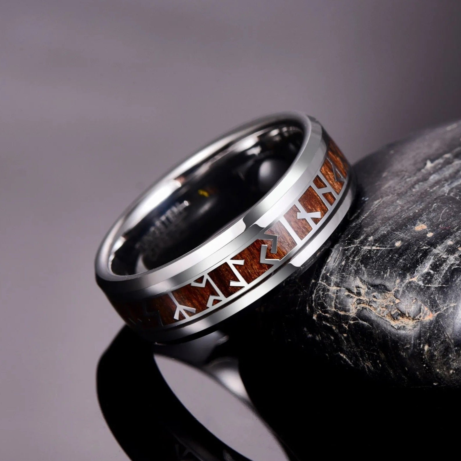 Viking Rune ring with silver and wood inlay, resting on a rock background