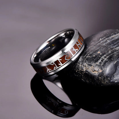 Viking rune ring in silver with a wood inlay, resting on a stone surface.