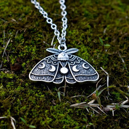 Antiqued silver moth design decorated with stars and the changing phases of the moon.
