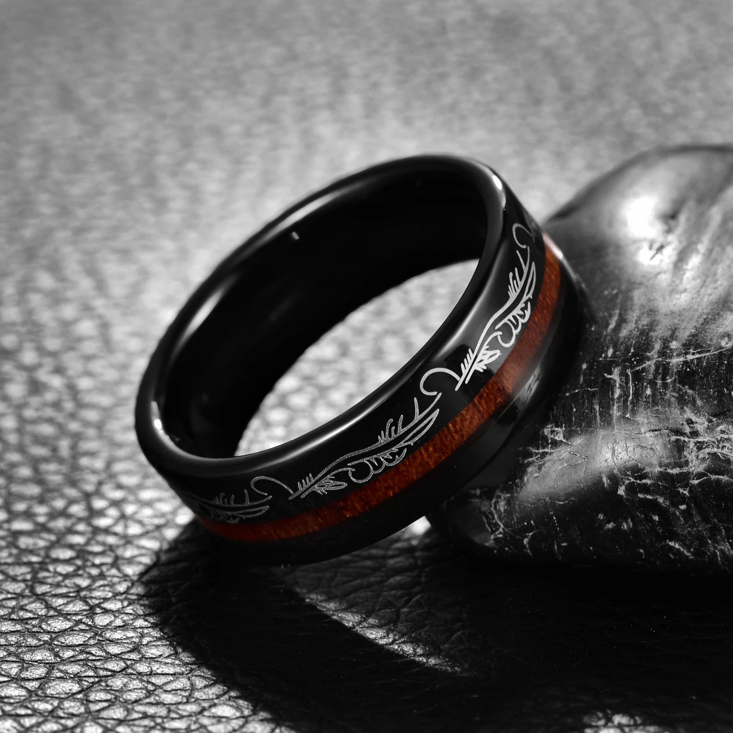 Black Tungsten ring with filigree feather detailing and offset acacia wood inlay, angled view