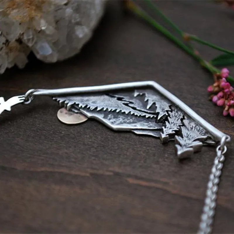 Detailed wilderness necklace showing a forested mountain landscape.