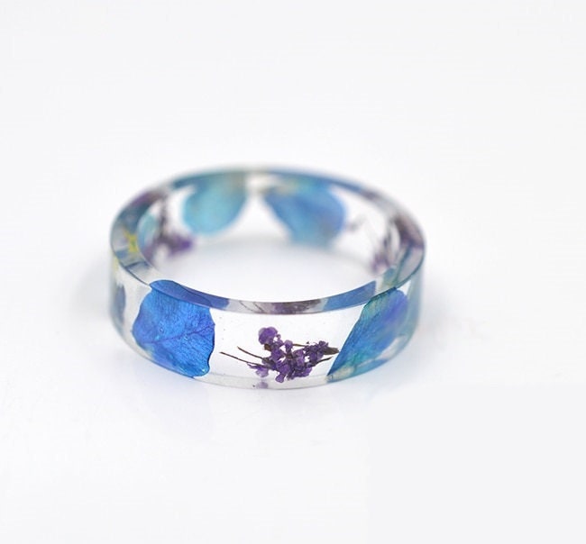 Flat botanical resin ring with real wildflowers visible around the transparent band.