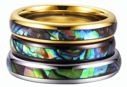 A stack of gold, silver, and black Tungsten rings, each featuring an abalone shell inlay.