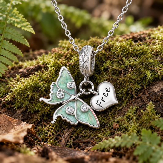 Luna moth necklace, crafted from sterling silver with pale green wings and a dangling heart charm.