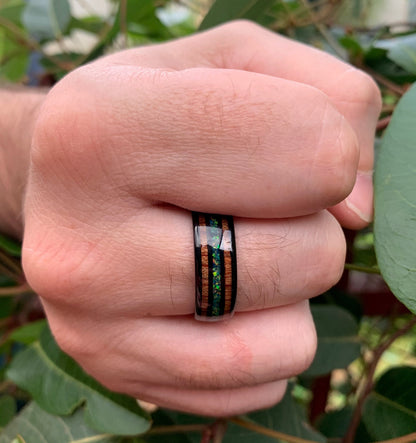 Close-up of a men's tungsten ring with acacia wood and green opal inlay on hand, showing the intricate details.