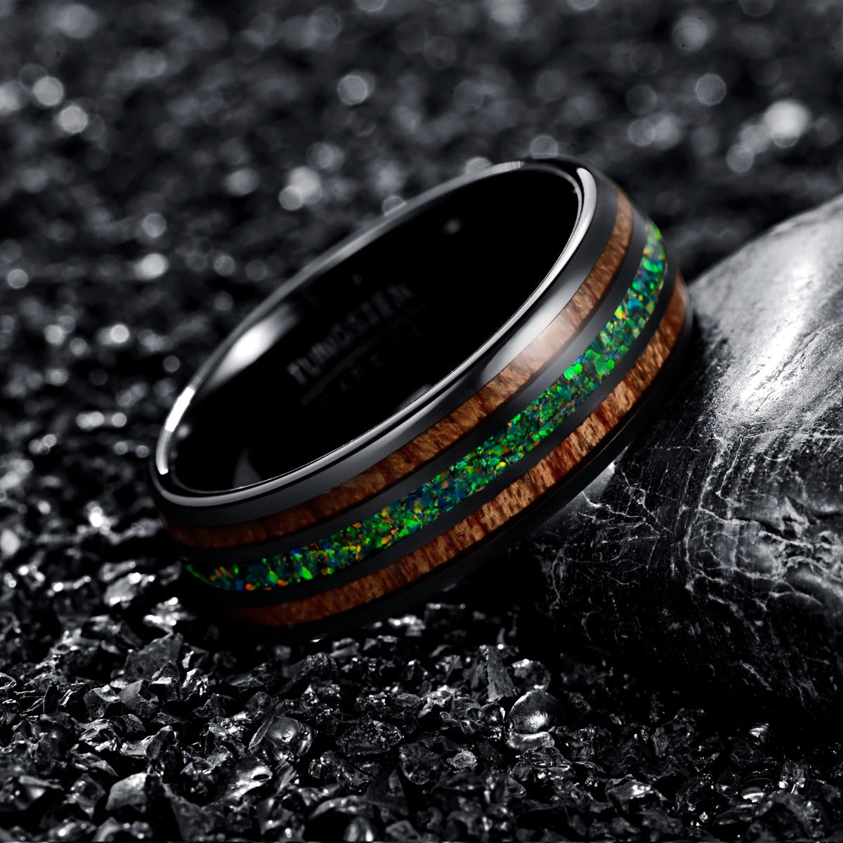 Side view of a men's tungsten ring with acacia wood and green opal inlay, displayed on black textured background.