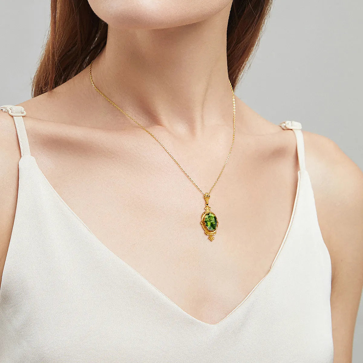 Yellow gold peridot necklace shown worn around the neck, with the faceted green gemstone catching the light.