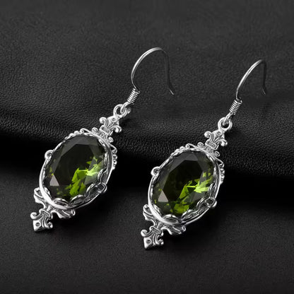 Sterling silver drop earrings featuring oval faceted peridot stones in decorative settings.