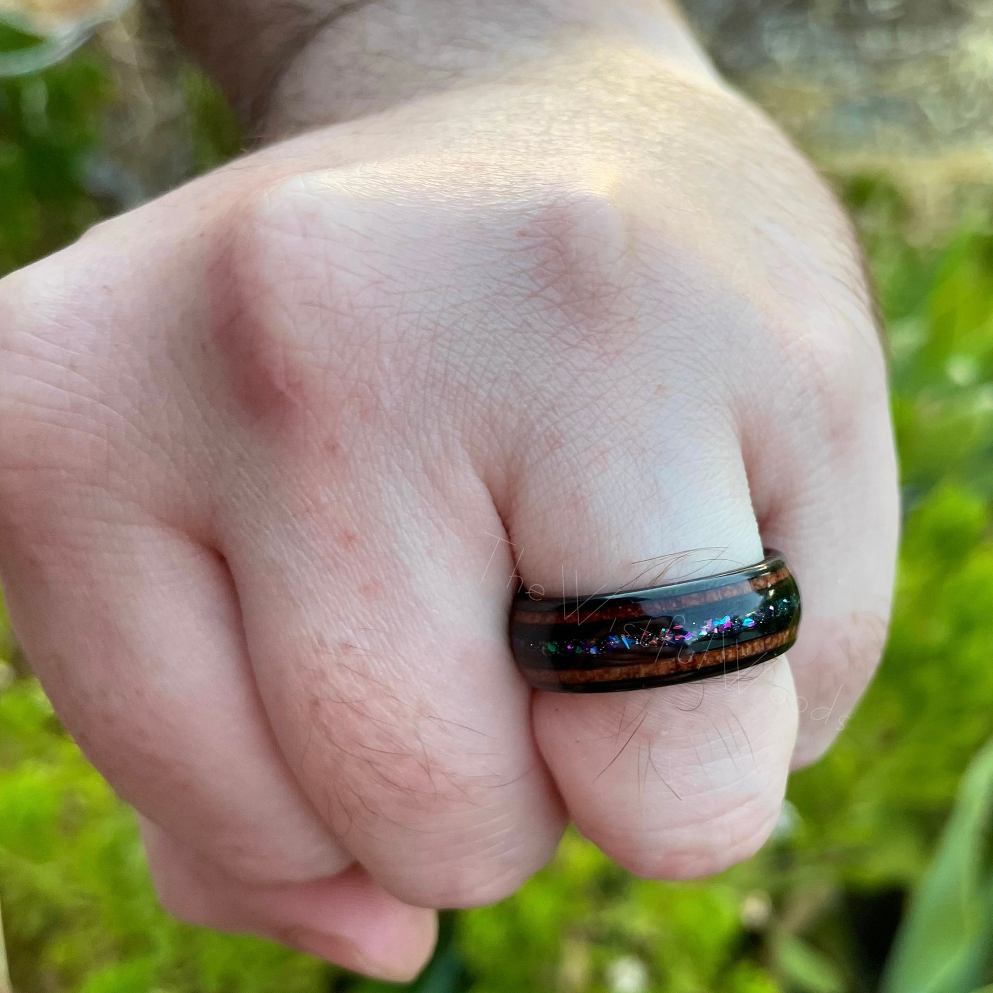 8mm black Tungsten supernova men's ring with Moon dust, acacia wood, and crushed opal inlay, worn on hand.