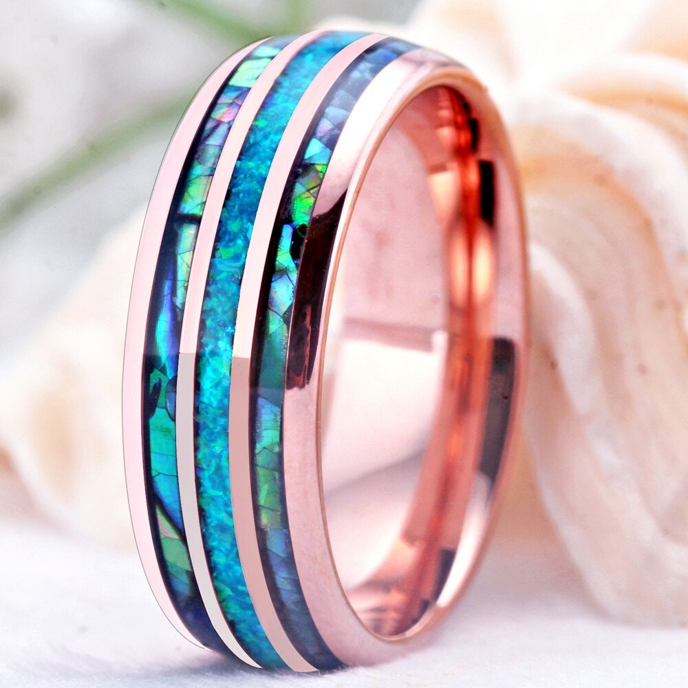 Close-up of blue opal and rainbow abalone shell inlay on a rose gold Tungsten wedding ring