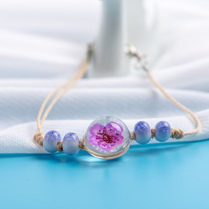 Boho-style bracelet with a real botanical specimen sealed beneath clear glass.