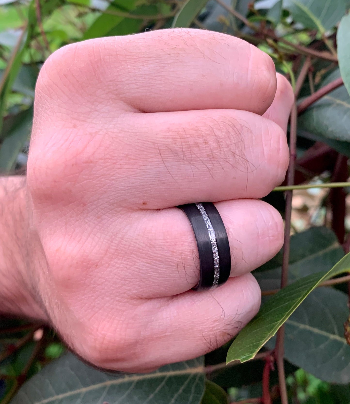 Carbon fiber mens rings displayed on a man's hand.