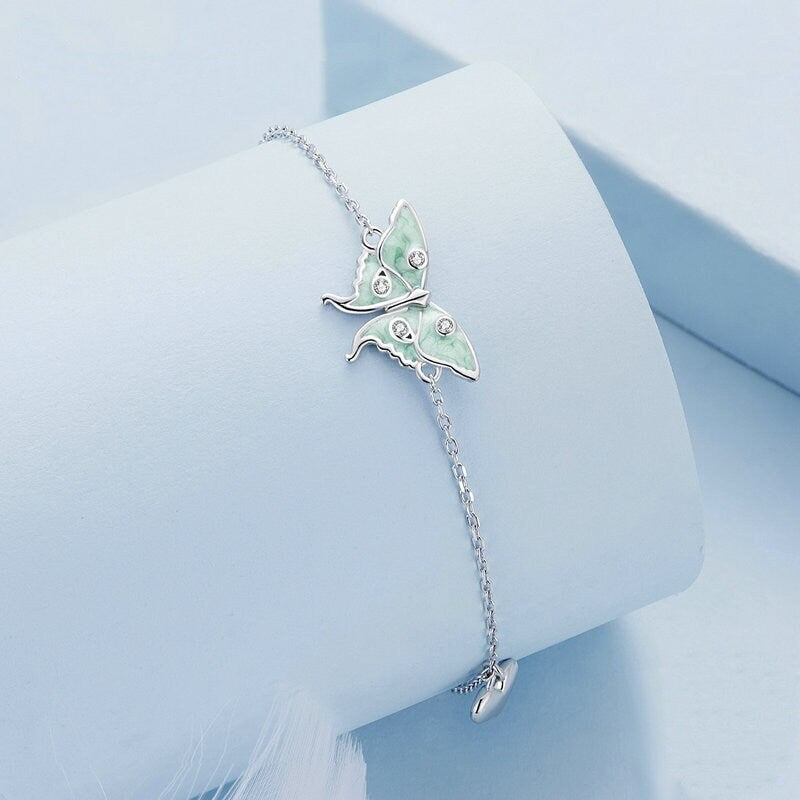 Close up of matching bracelet showing the delicate green wings and silver detailing.