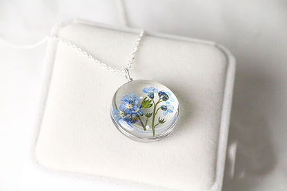 Delicate botanical pendant featuring real preserved blue flowers.