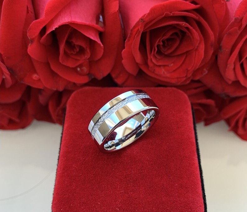 Flat band Tungsten men's ring with a Gibeon meteorite inlay, presented on a red velvet ring holder and surrounded by red roses.