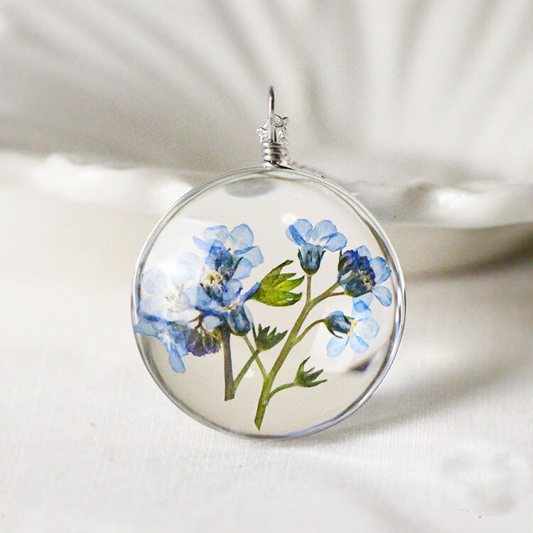 Forget me not necklace with real blue flowers preserved in a clear glass pendant.