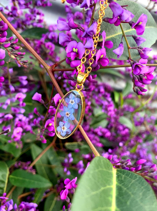 Forget me not pendant with real blue flowers inside a delicate oval setting.