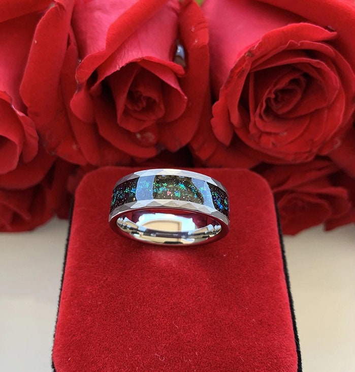 Galaxy rings with iridescent opal inlay, displayed on a red velvet background with roses.