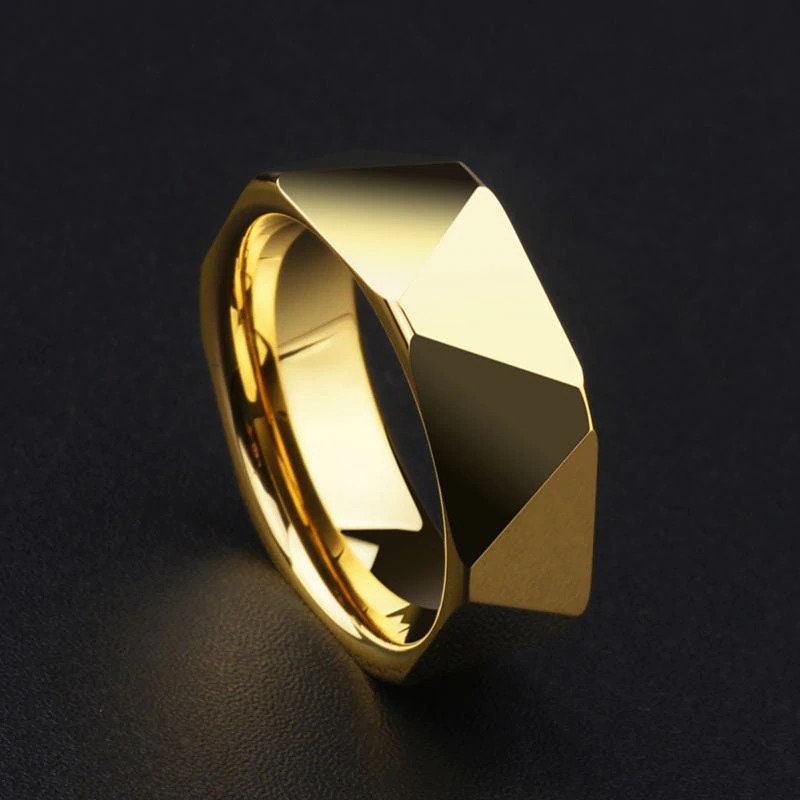 Geometric rings in gold Tungsten, reflecting light on a black background.