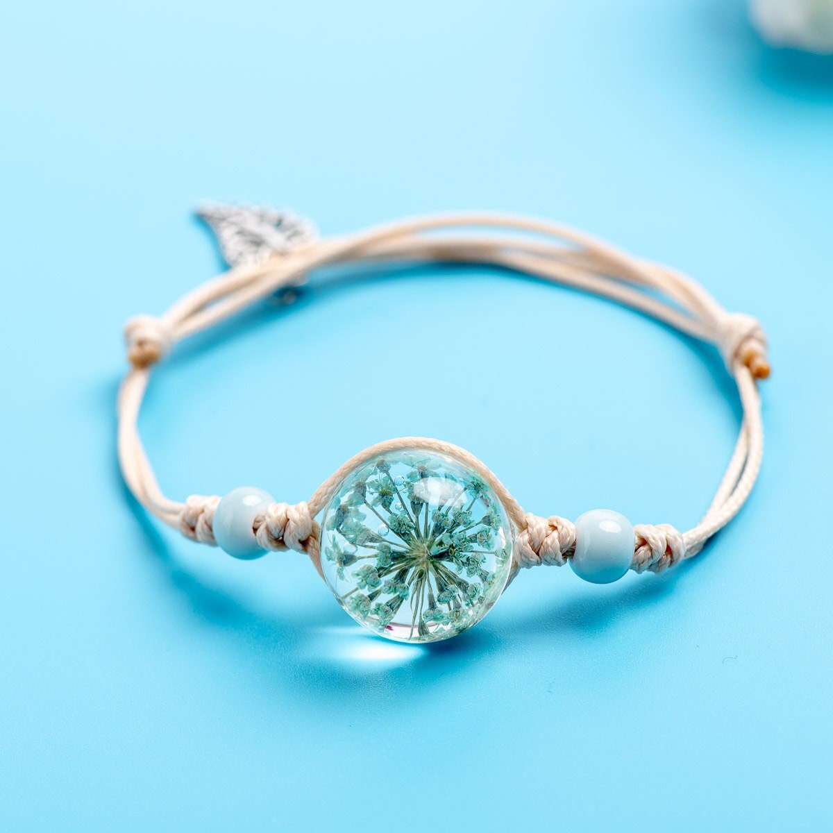 Real flower bracelets featuring a genuine pressed bloom with soft bead details and an adjustable cord.