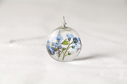 Real flower jewelry with genuine blue forget-me-nots preserved inside a glass pendant.