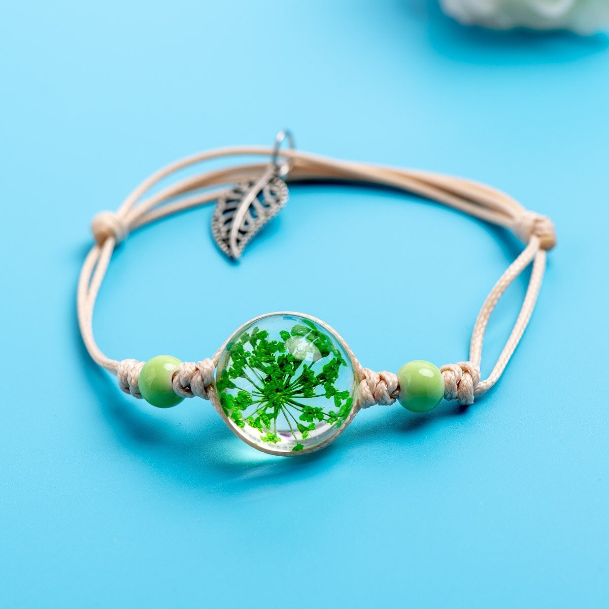 Adjustable cord bracelet with a real preserved natural element framed in a round glass setting.