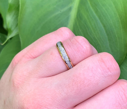 Close-up of a rose gold Tungsten meteorite ring against green foliage