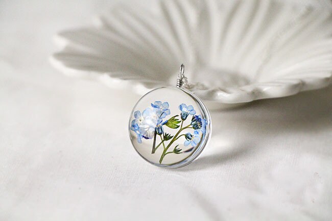 Round glass floral pendant showing the natural detail of the preserved blossoms.