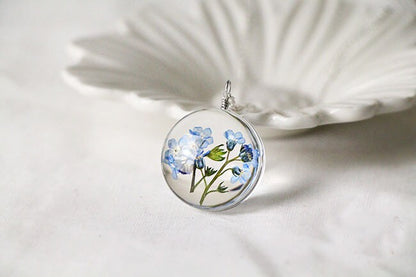 Round glass floral pendant showing the natural detail of the preserved blossoms.