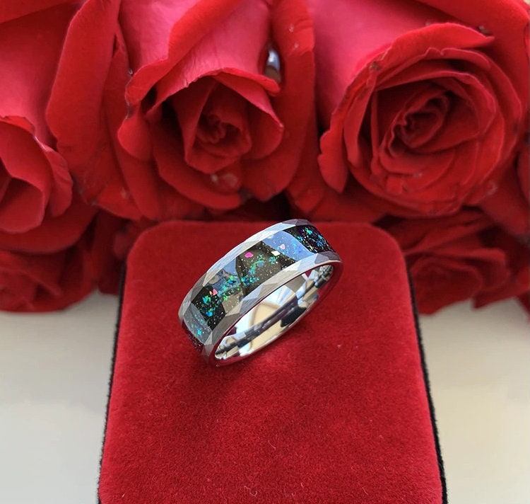 Silver Tungsten hammered men's ring with iridescent opal inlay, placed on red ring box with roses in background.